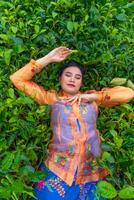 un indonesiano donna è dire bugie su un' verde tè giardino mentre su vacanza foto