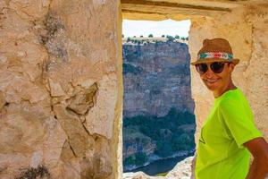 sorridente donna di mezza età con cappello accanto alla finestra di pietra sul fiume foto