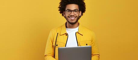 contento riuscito africano americano uomo libero professionista guardare a telecamera con il computer portatile su giallo sfondo foto