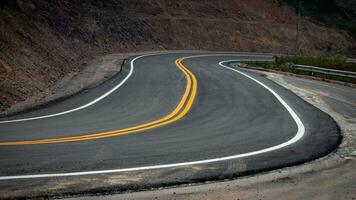 il asfalto strada ha giallo e bianca traffico Linee attraversamento il montagne. foto