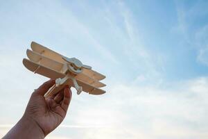 la libertà concetto, umano mano Tenere di legno aereo su il tramonto cielo sfondo foto