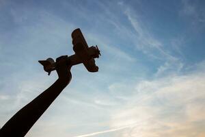 silhouette di contento bambini giocando un' di legno giocattolo aereo su il tramonto cielo sfondo. foto