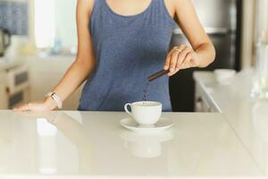 donna mano scrosciante immediato caffè bustina in un' tazza. foto