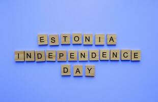 agosto 20, Estonia indipendenza restauro giorno, minimalista bandiera con il iscrizione nel di legno lettere su un' blu sfondo foto