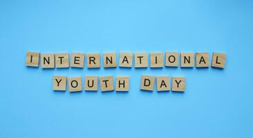 agosto 12, internazionale gioventù giorno, minimalista bandiera con il iscrizione nel di legno lettere su un' blu sfondo foto