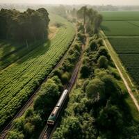 un aereo Visualizza di un' treno passaggio attraverso un' lussureggiante campagna generativo ai foto