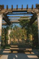 vecchio panchina nel colonnato a il collina giardino e pergola con cielo nel sfondo foto