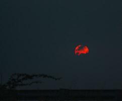 un' rosso sole nel il cielo foto