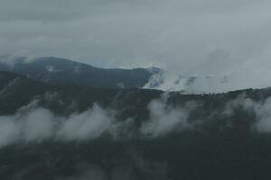 bellissimo panoramico Visualizza di nebbia e nuvole nel lontano strati montagne gamma con blu cielo nel mattina foto