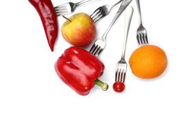un alimento dietetico sano. pomodorini freschi, peperoncino, cetriolo, mela e arancia frutta su forchette su sfondo bianco. mangiare sano e cibo vegetariano, concetto di cucina.
