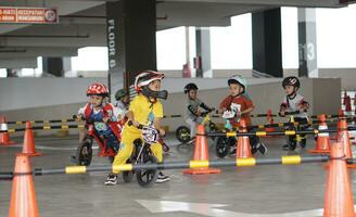 depok-indonesia, 29 07 2023 - indonesiano bambini a partire dal 2-5 anni vecchio gare su equilibrio bicicletta nel un' parcheggio la zona, sportività formazione foto