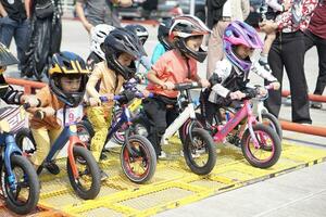 depok-indonesia, 29 07 2023 - indonesiano bambini a partire dal 2-5 anni vecchio pronto per gare su equilibrio bicicletta nel un' parcheggio la zona, sportività addestramento. foto