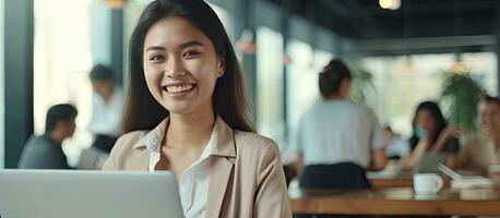 sorridente asiatico donna nel opera abbigliamento usi il computer portatile a ufficio ricercando felicemente radiante positivo energia esecuzione attività commerciale Piano foto