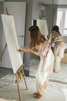giovane donna artista pittura su tela su il cavalletto a casa nel Camera da letto - arte e creatività concetto foto