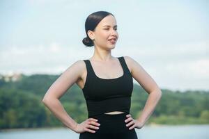 giovane donna nel nero abbigliamento sportivo esercizio all'aperto. fitness e salutare stile di vita concetto. il bianca ragazza fa gli sport nel il parco. foto