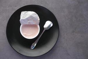 yogurt fresco in un contenitore di plastica su sfondo nero
