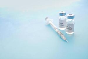 vaccino contro il coronavirus e siringa su sfondo blu foto