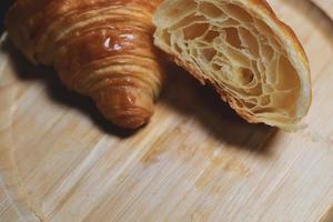 i croissant sono posti su un fondo di legno. prodotti da forno su sfondo isolato
