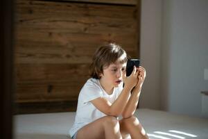 poco ragazzo con un' cellulare foto