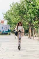 asiatico donna equitazione elettrico scooter nel il parco, stile di vita concetto foto