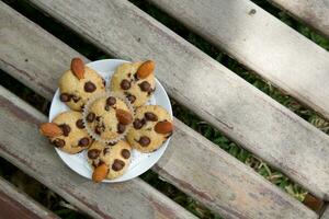 cioccolato patata fritta muffin su un' piatto su un' di legno panchina foto