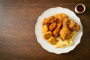 pollo fritto con patatine fritte e pepite sul piatto foto