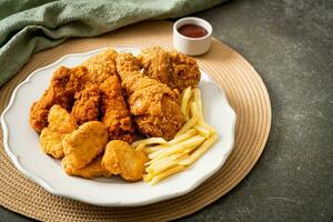 pollo fritto con patatine fritte e pepite sul piatto foto