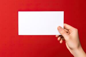 un' umano mano Tenere un' vuoto foglio di bianca carta o carta isolato su rosso sfondo. ai generato foto