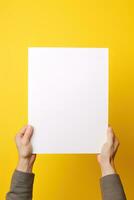 un' umano mano Tenere un' vuoto foglio di bianca carta o carta isolato su giallo sfondo. ai generato foto