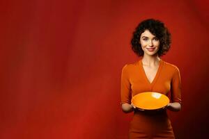 giovane bellissimo elegante donna Tenere un vuoto piatto o piatto isolato su arancia sfondo con copia spazio. ai generato foto
