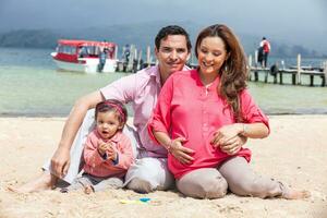 giovane coppia in attesa per loro secondo bambino avendo divertimento con loro bambino ragazza a il bellissimo bianca spiaggia di lago tota collocato nel il Dipartimento di boyaca a 3.015 metri sopra mare livello nel Colombia foto