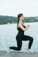 giovane donna nel nero abbigliamento sportivo esercizio all'aperto. fitness e salutare stile di vita concetto. il bianca ragazza fa gli sport nel il parco. foto