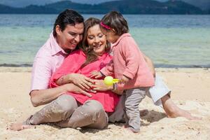 giovane coppia in attesa per loro secondo bambino avendo divertimento con loro bambino ragazza a il bellissimo bianca spiaggia di lago tota collocato nel il Dipartimento di boyaca a 3.015 metri sopra mare livello nel Colombia foto