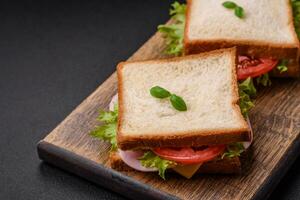 delizioso Sandwich con pane abbrustolito, prosciutto, pomodori, formaggio e lattuga foto