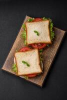 delizioso Sandwich con pane abbrustolito, prosciutto, pomodori, formaggio e lattuga foto