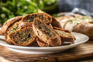 Marrone al forno pane con erbe aromatiche affettato e immagazzinato su un' piatto foto