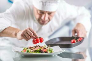 capocuoco nel il cucina di il Hotel o ristorante decora il cibo appena prima servendo foto