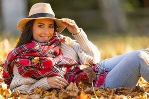 ritratto di un' contento giovane donna nel autunno attrezzatura durante autunno di le foglie foto