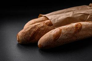 francese baguette pane su un' buio strutturato calcestruzzo sfondo foto