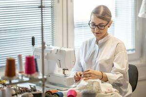 mestiere sarto laboratorio con donna seduta dietro a il cucire macchina, fabbricazione Abiti foto