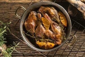 arrostito anatra gambe nel padella con arance erbe aromatiche rosso cavolo e Patata pankaces foto