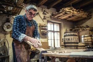 edificio di legno botti per memorizzazione anziano alcool di un più vecchio uomo nel un' Vintage ▾ laboratorio foto