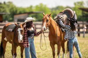 Due femmina amici porzione uno un altro per mettere il sella via il cavallo dopo un' estate cavalcata foto