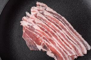 fresco crudo Bacon tagliare in fette con sale, spezie e erbe aromatiche foto