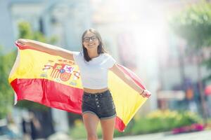contento ragazza turista a piedi nel il strada con spagnolo bandiera foto