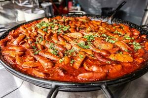 grande strada cibo padella pieno di rosso salsiccia stufato con prezzemolo su superiore di il venditore foto