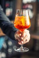 aperol spritz bere. barista mano Tenere bicchiere con aperol spritz bevanda foto