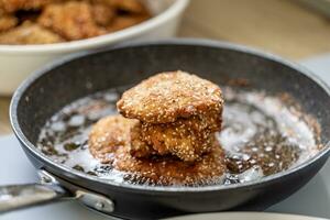 schnitzels nel briciole di pane ammucchiati su un' nero padella pieno di frittura olio foto