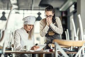 shock e sorpresa su facce di femmina gastro dipendenti seduta al di sopra di numeri dopo ore nel il bar foto