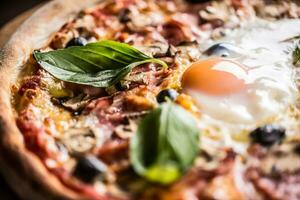 Pizza capricciosa capriccioso tradizionale italiano pasto a partire dal prosciutto funghi carciofi uovo parmigiano olive e basilico foto